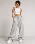 Model wearing oversized wide-leg sweatpants in heather grey with white crop tank and sneakers