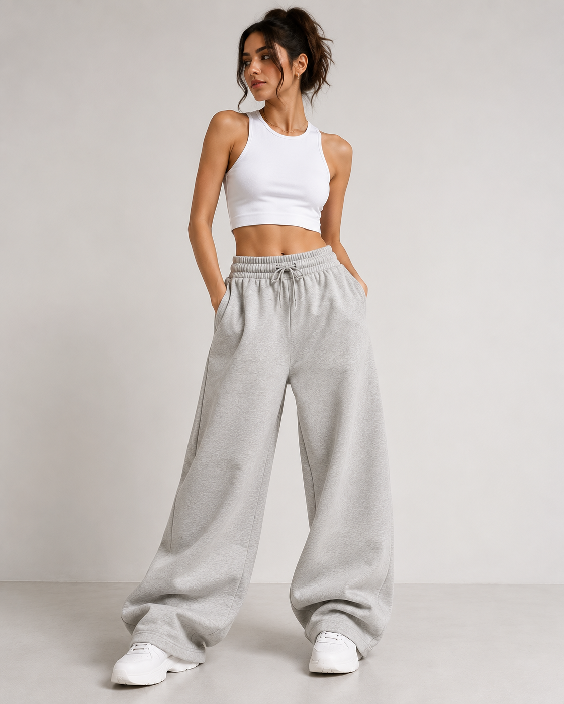 Model wearing oversized wide-leg sweatpants in heather grey with white crop tank and sneakers